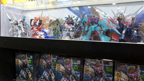 Exhibición de juguetes de Gundam en una juguetería, con múltiples modelos de mobile suits organizados en estanterías