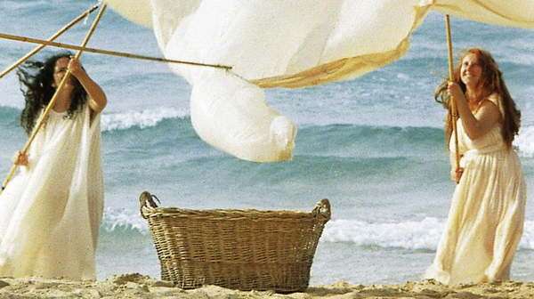 Escena de Nostos: The Return con un grupo de mujeres en una playa mediterránea