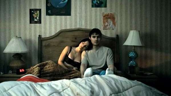 Escena de Obsesión con los protagonistas acostados en una cama durante una secuencia de tensión sobrenatural.